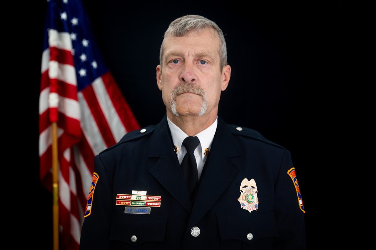 A fire chief in dress uniform in front of an American flag
