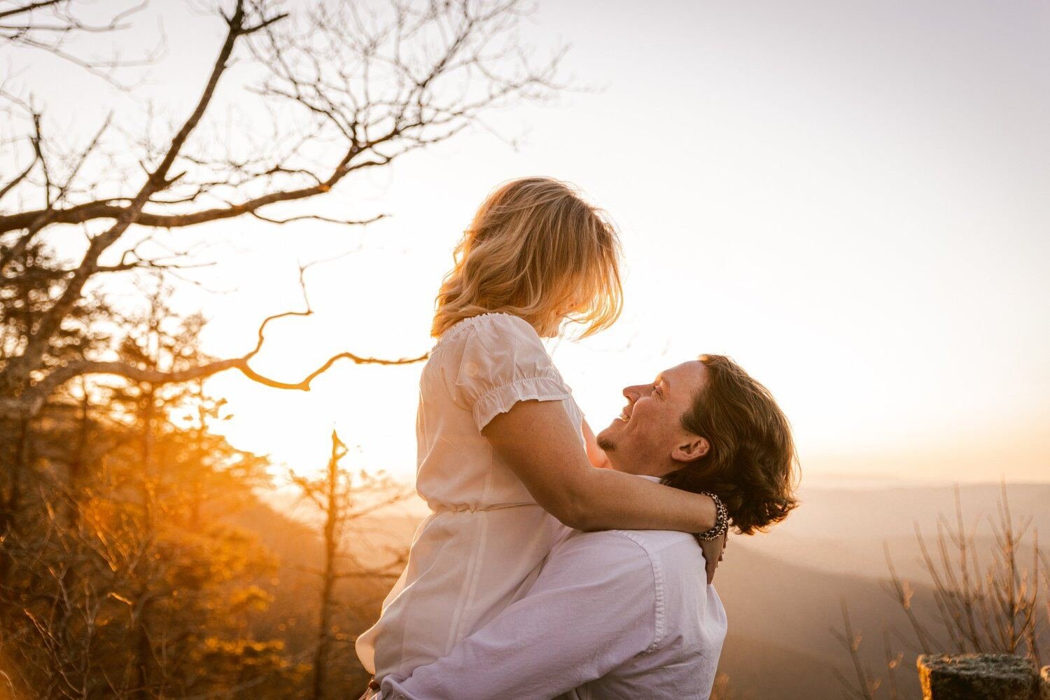 A couple embracing on a hillside at sunset